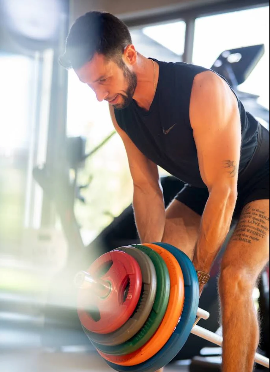 Rut In Fit stüdyosunda, gün ışığında renkli ağırlık plakalarıyla antrenman